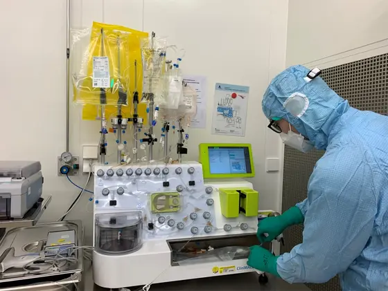 Eine Person in Schutzkleidung bedient ein medizinisches Gerät, das mit verschiedenen Schläuchen und einer Steuerkonsole ausgestattet ist. Das Gerät scheint für medizinische Anwendungen konzipiert zu sein, möglicherweise zur Infusion oder Patientenüberwachung.