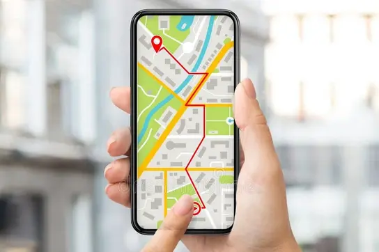 Eine Hand hält ein Smartphone, auf dessen Bildschirm eine Kartenansicht mit verschiedenen Straßen und markierten Punkten angezeigt wird. Eine Fingerberührung deutet auf eine Position auf der Karte hin.