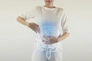 Frau hält Hände auf den Bauch, überlagert von einer grafischen Darstellung des Darms.