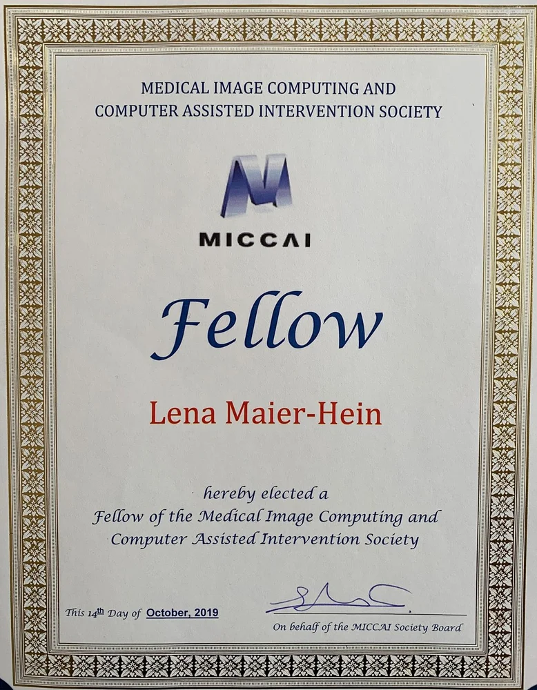 Certificate recognizing Lena Maier-Hein as a Fellow of the Medical Image Computing and Computer Assisted Intervention Society (MICCAI), awarded on October 18, 2019. The document features the MICCAI logo and includes a signature from the society's board.