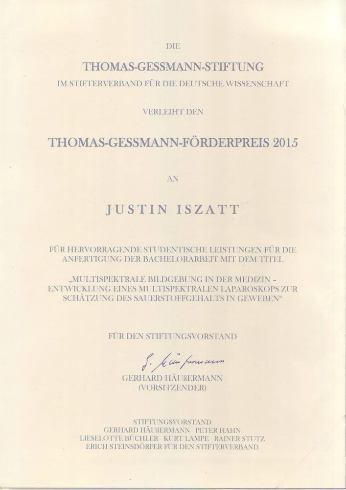 Certificate from the Thomas-Gessmann Foundation awarding the Thomas-Gessmann Förderpreis 2015 to Justin Iszatt. It recognizes outstanding academic achievements for a bachelor's thesis titled "Multimedia-Based Development of a Multimedia-Learning Notebook for Estimating Mastery Levels in Subjects." Includes signatures from the board members.