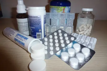Eine Sammlung von Medikamenten und Nahrungsergänzungsmitteln auf einem Tisch. Dazu gehören verschiedene Pillenpackungen, Flaschen mit Tropfen und Pulver sowie Blisterpackungen mit Tabletten. Die Produkte sind in unterschiedlichen Größen und Formen angeordnet.
