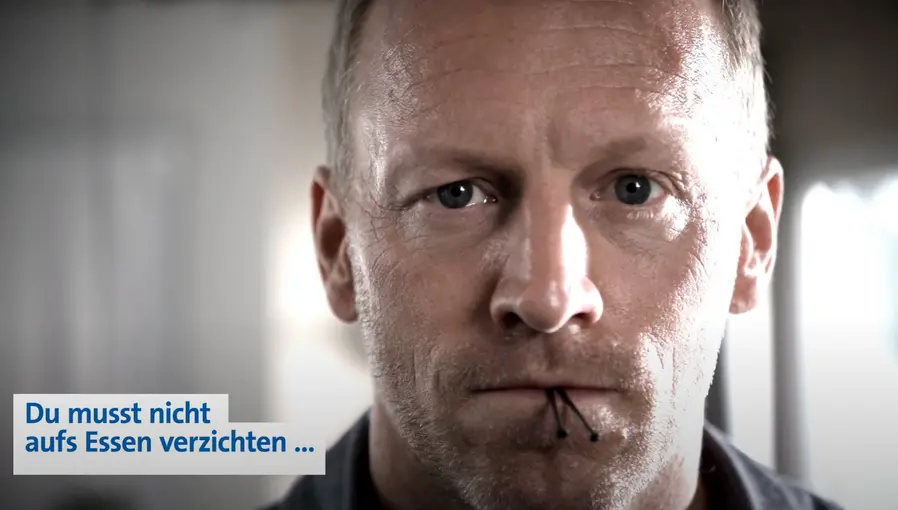 Mann mit ernstem Blick und zwei Nägeln zwischen den Lippen; Text unten links: „Du musst nicht aufs Essen verzichten …“