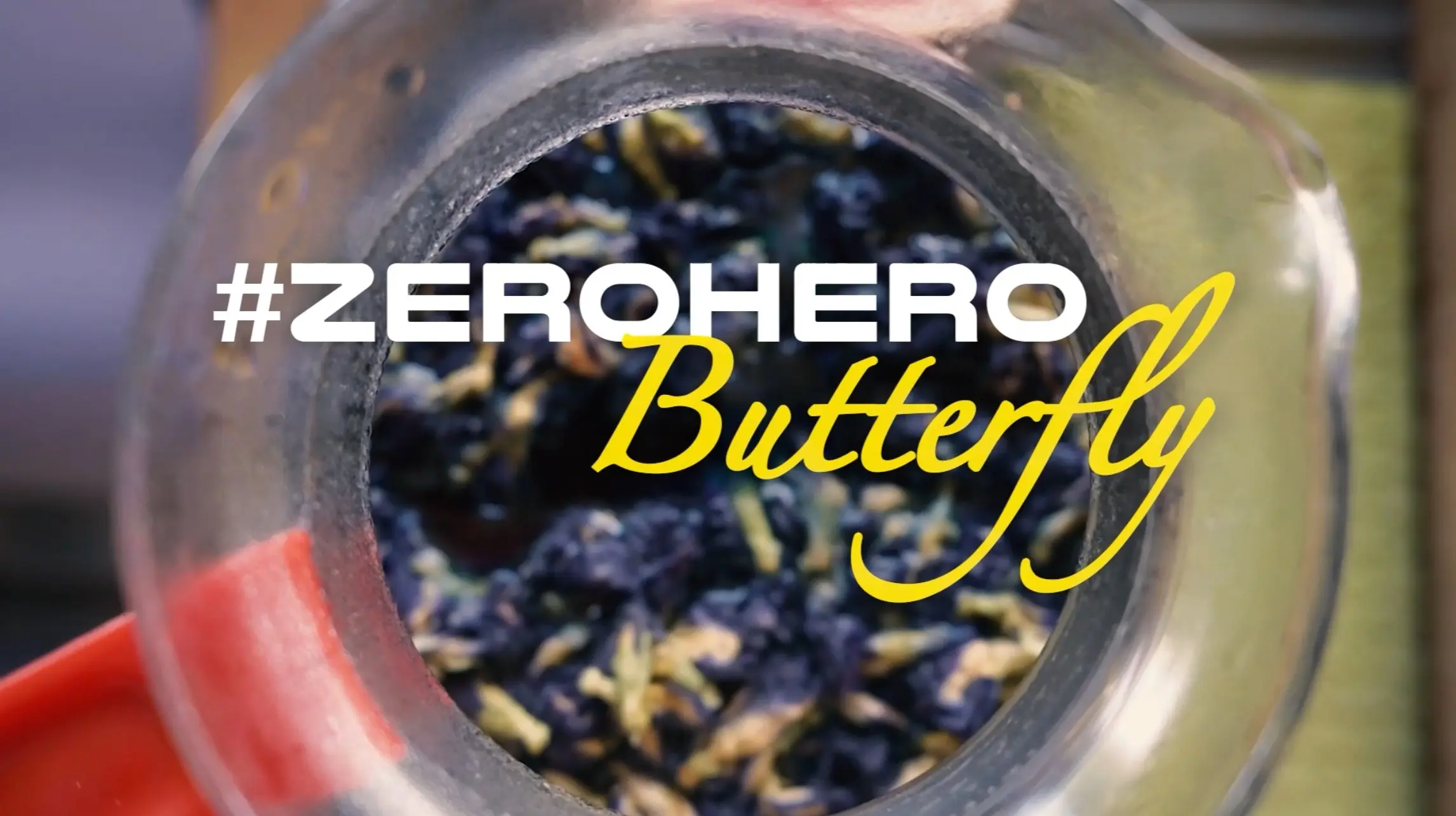 Ein Glas mit einer bunten Mischung aus getrockneten Blüten, das von oben betrachtet wird. Darüber steht der Text „#ZEROHERO“ und „Butterfly“ in stilvollen Schriftarten.