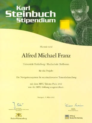 The image is a certificate for the Karl Steinbuch Scholarship awarded to Alfred Michael Franz from the University of Heidelberg for a project on a navigation system for minimally invasive tumor treatment. The certificate is dated March 16, 2012, and includes signatures.