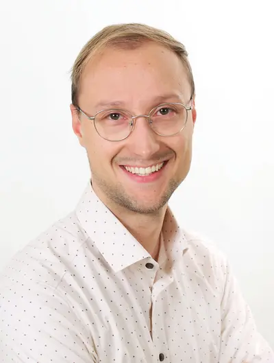 Lächelnder Mann mit blonden Haaren und weißem Hemd. 