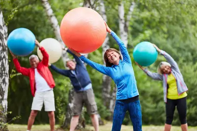 Seniorengruppe mit Gymnastikball, die gemeinsam Rückenübungen macht