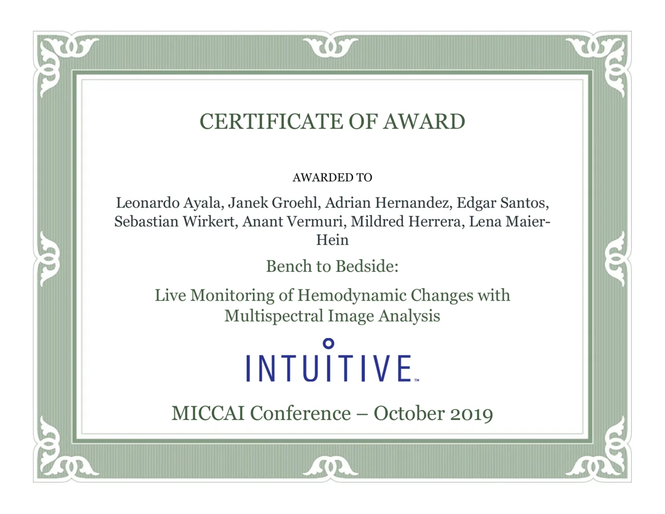 Certificate of Award presented to a group of individuals for their work titled "Live Monitoring of Hemodynamic Changes with Multispectral Image Analysis." Awarded at the MICCAI Conference in October 2019, sponsored by Intuitive. The certificate is framed with an ornate border.