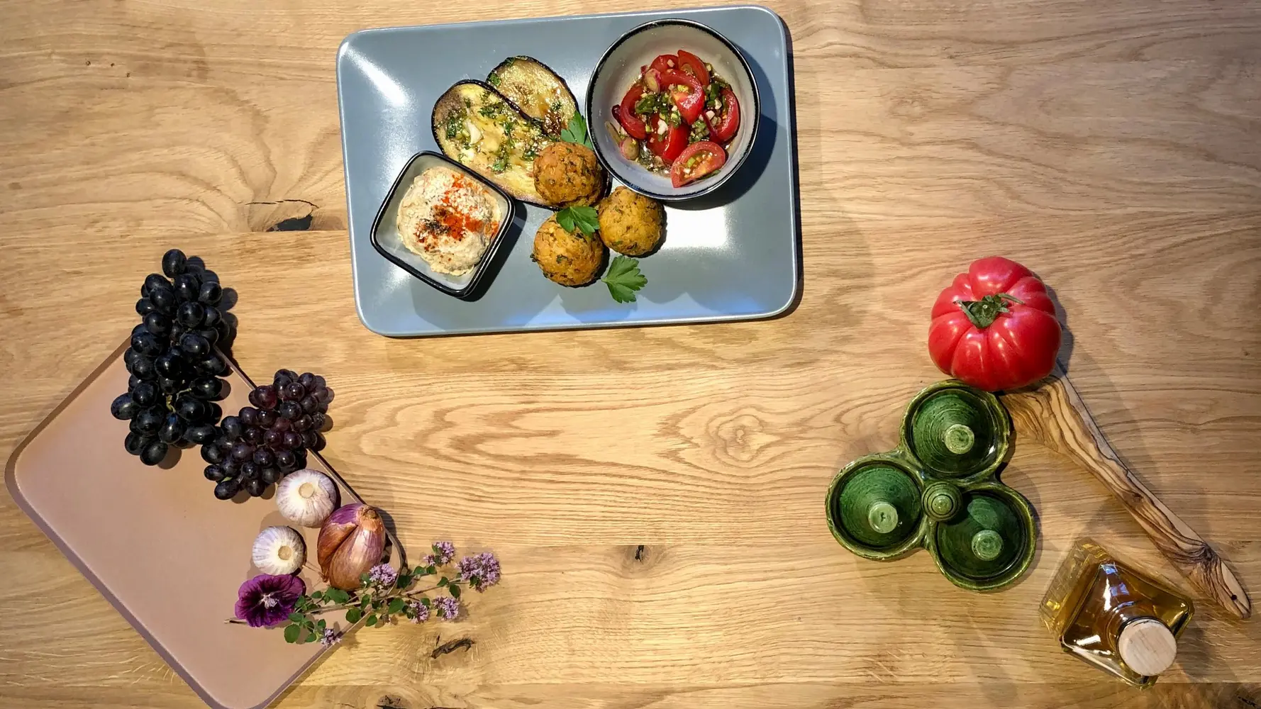 Falafel, gebratene Aubergine, Tomatensalat und Hummus auf rechteckigem Teller.