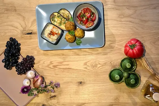 Falafel, gebratene Aubergine, Tomatensalat und Hummus auf rechteckigem Teller.