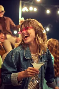 Zwei Frauen mit Cocktails in der Hand bei einer Party im Freien.