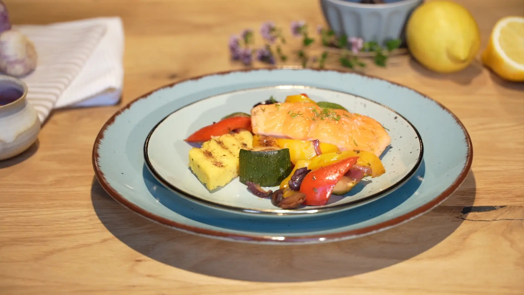 Lachsfilet mit Grillgemüse auf einem hellblauen Teller.