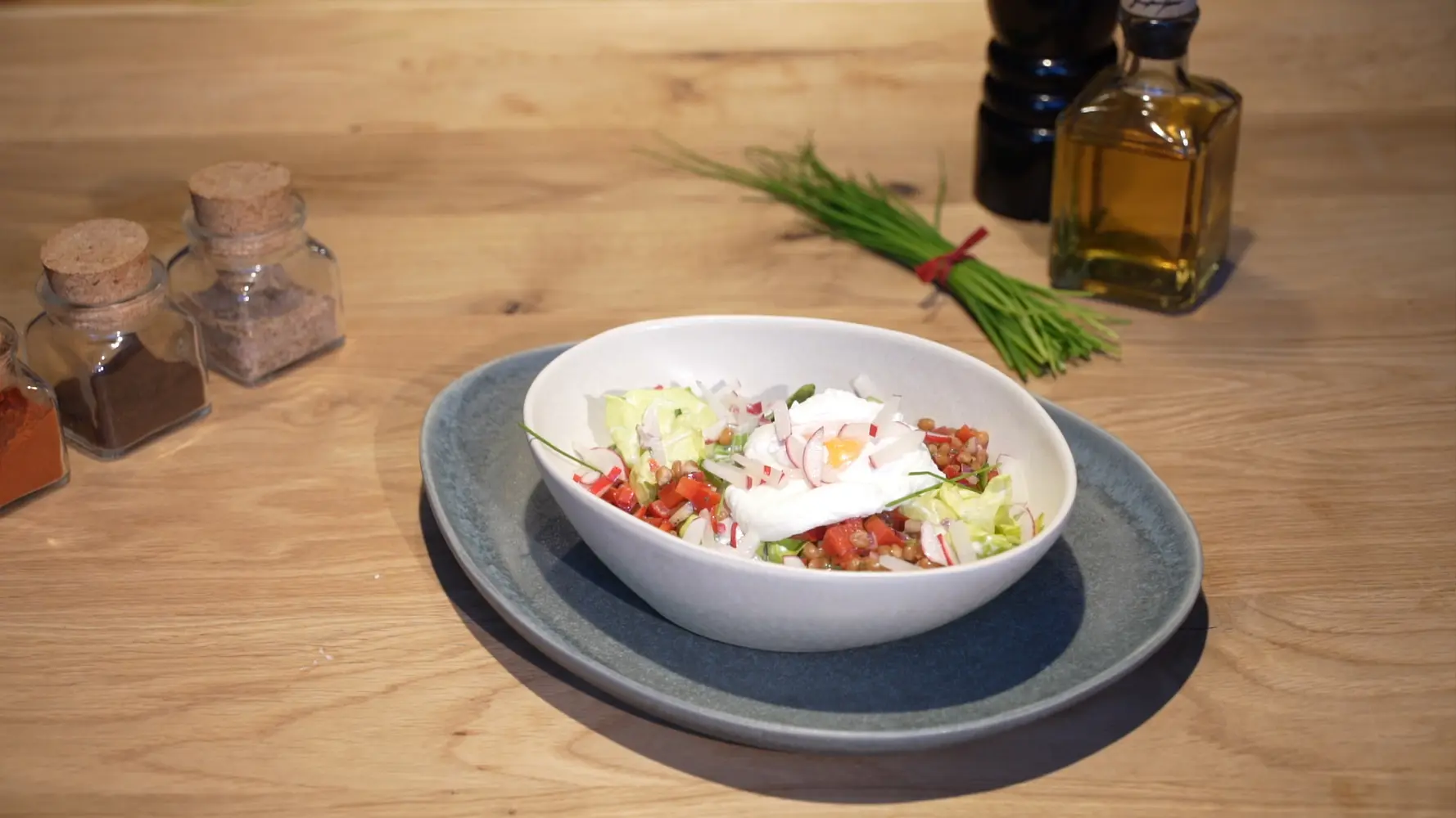 Frischer Salat mit Zartweizen, Radieschen und pochiertem Ei in einer Schale.