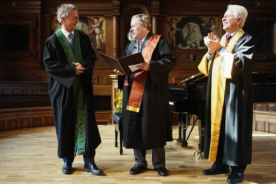 Hans-Georg Kräusslich (l.), Dean of the Heidelberg Medical Faculty, and Bernhard Eitel, Rector of Heidelberg University (r.), congratulate Webster K. Cavenee.